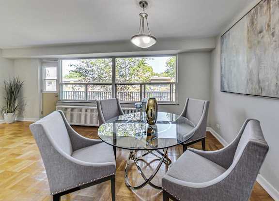 a dining room with a glass table and chairs and a large window