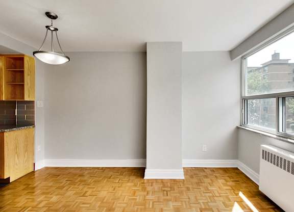 an empty living room with a large window and wood flooring
