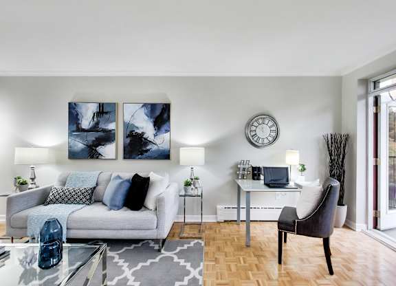 a living room with a couch and a chair and a desk with a laptop