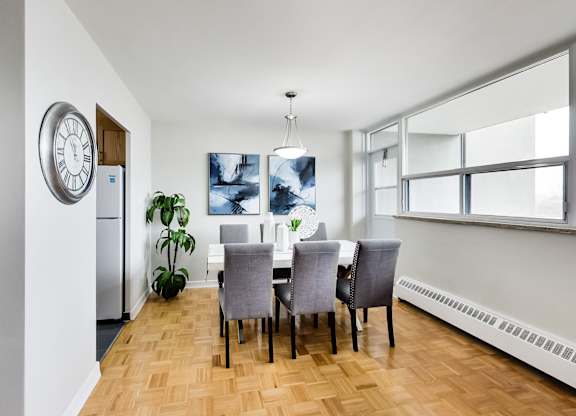 a dining room with a table and chairs and a large clock on the wall