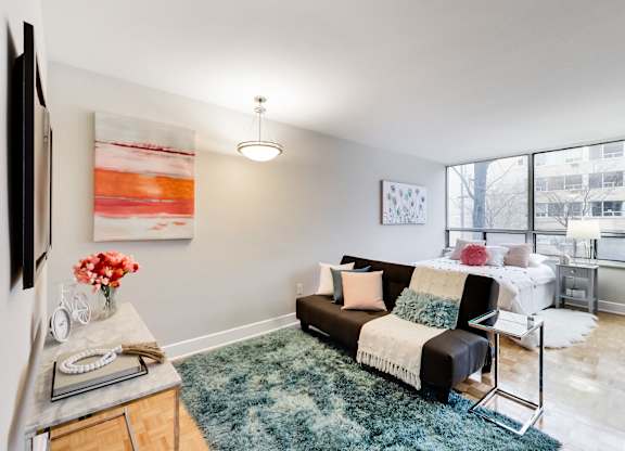A living room with a couch, a rug, a table, and a painting on the wall.
