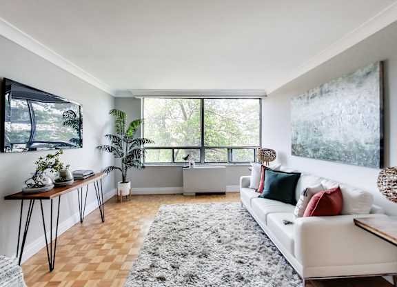 A living room with a white couch and a large window.
