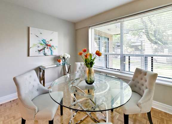 a dining room with a glass table and chairs and a large window