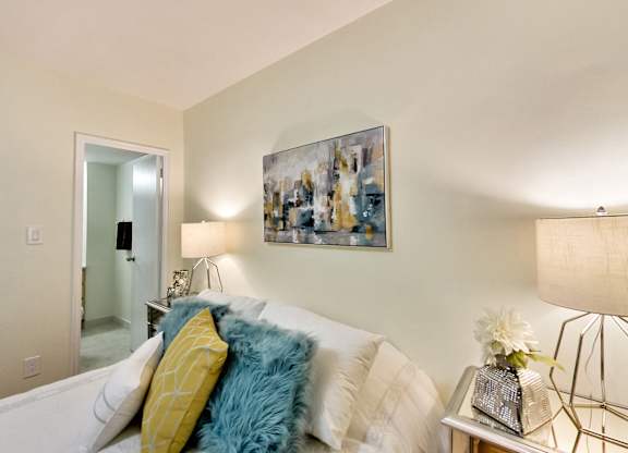 A living room with a white couch and a painting on the wall.
