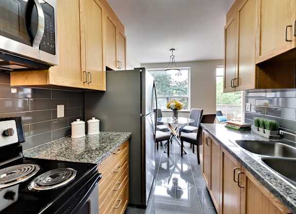 a kitchen with stainless steel appliances and wooden cabinets and a table with chairs