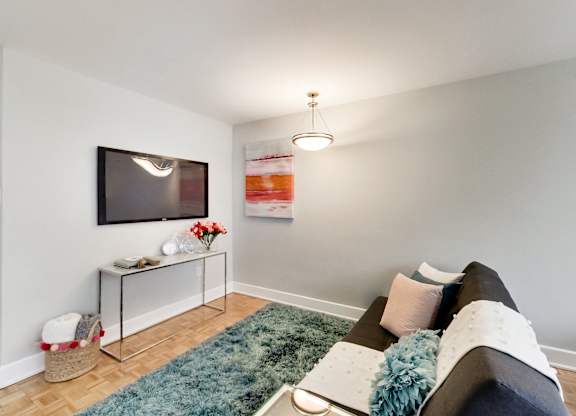 A living room with a grey couch and a television on the wall.
