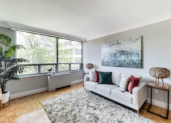 A living room with a white couch and a large painting on the wall.