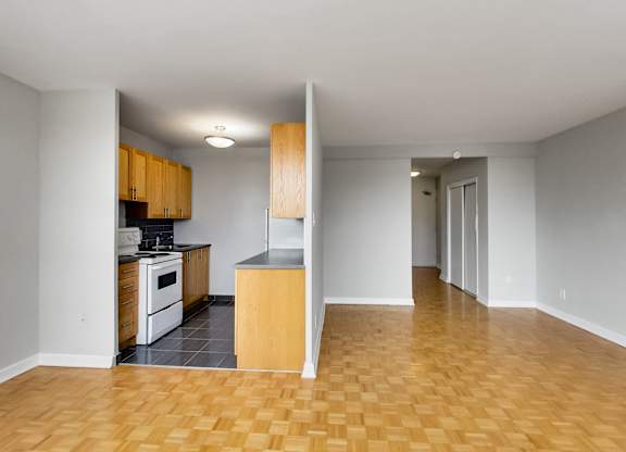 an empty living room and kitchen with wood flooring and white appliances