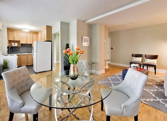 a living room with a glass table and chairs and a kitchen