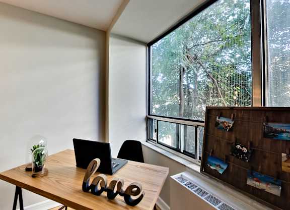 A wooden table with a laptop and a plant on it with a word LOVE on the table.