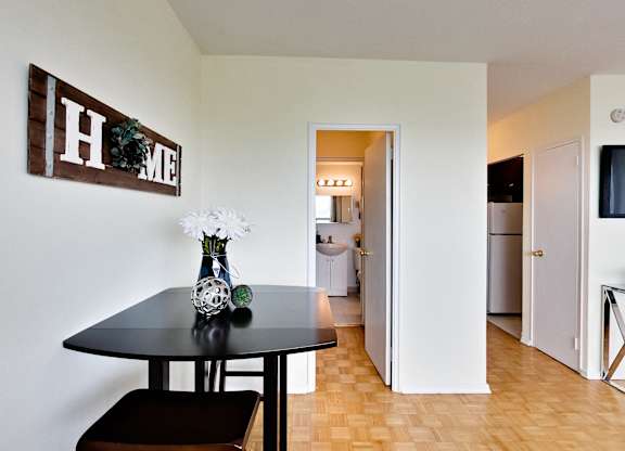 A black table with a vase of flowers on it in a room with a wooden floor.