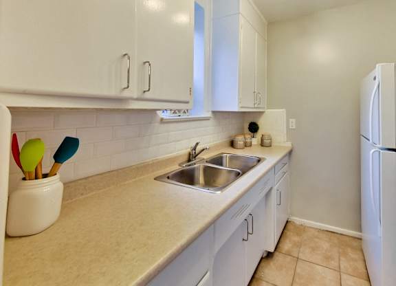 a kitchen with white cabinets and a sink and a refrigerator