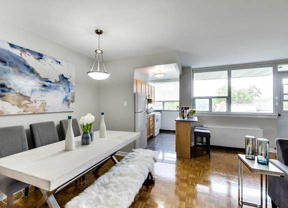 a dining room with a white table and chairs and a kitchen