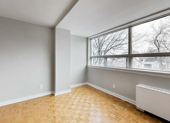 an empty living room with a large window and wood flooring