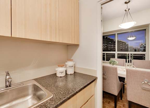 A kitchen with a sink and a dining table with chairs.