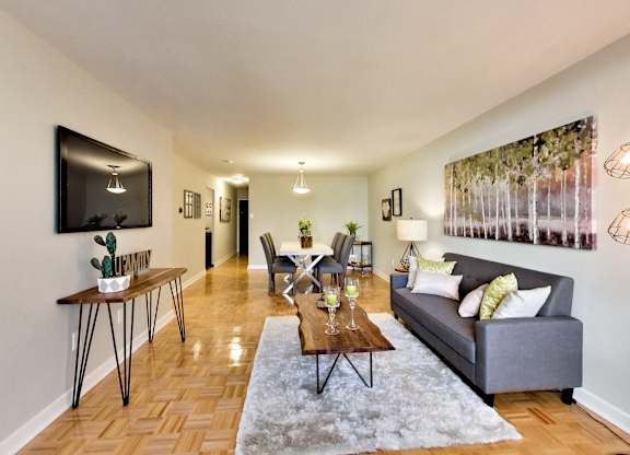 A living room with a grey couch, a coffee table, and a painting on the wall.