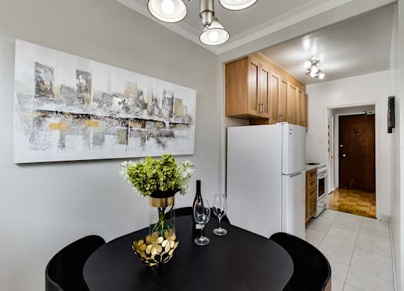 a kitchen and dining room with a black table and chairs and a refrigerator