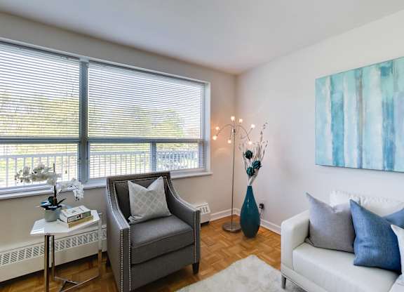 a living room with a couch and a chair and two windows