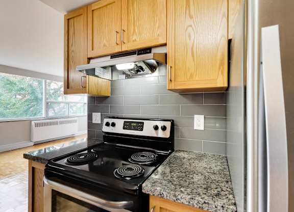 an empty kitchen with granite countertops and a black stove