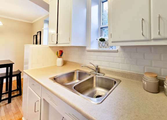 a kitchen with a stainless steel sink and white cabinets