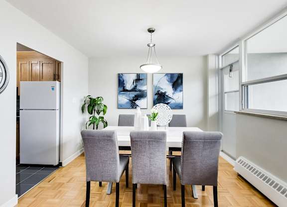 a dining room with a white table and chairs and a refrigerator
