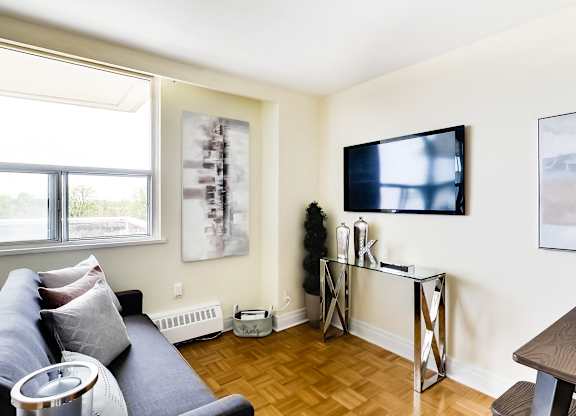 A living room with a blue couch and a television on the wall.