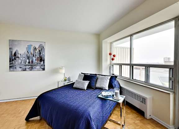 A bedroom with a blue bedspread and a painting on the wall.