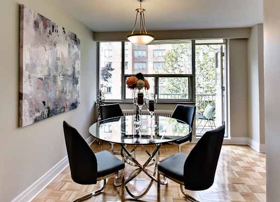 a dining room with a glass table and chairs and a large painting