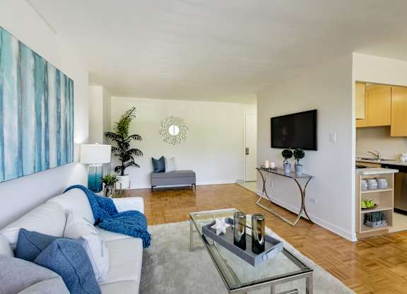 a living room with a white couch and a glass coffee table and a television