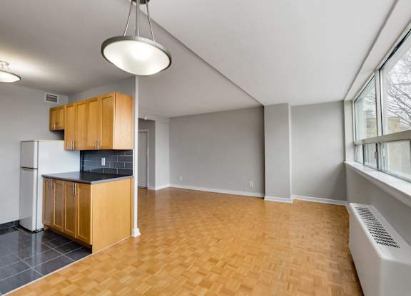 an empty living room with a kitchen and a large window