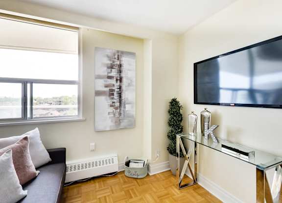 A living room with a couch, a television, and a painting on the wall.