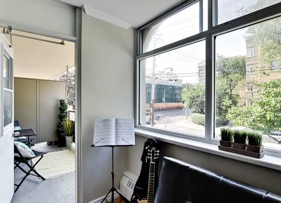 A room with a guitar, a chair, a music stand and a window.