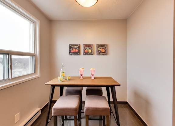 a dining room with a table and three chairs and a window
