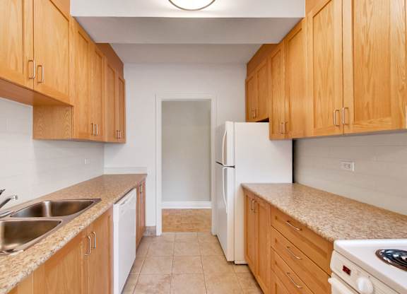 an empty kitchen with wooden cabinets and a white refrigerator