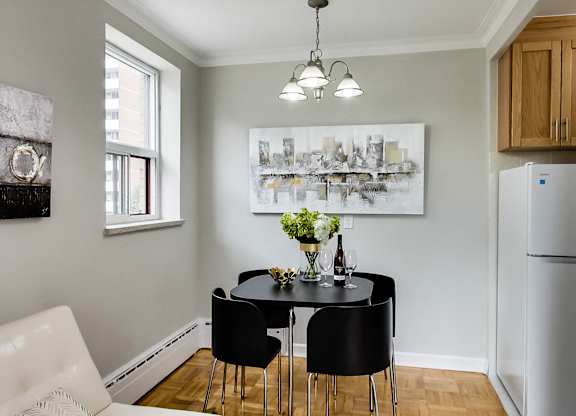 a dining room with a black table and chairs and a refrigerator