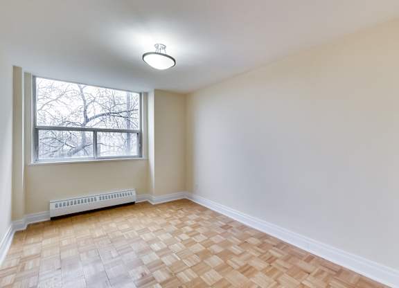 A room with a window and a radiator on the floor.
