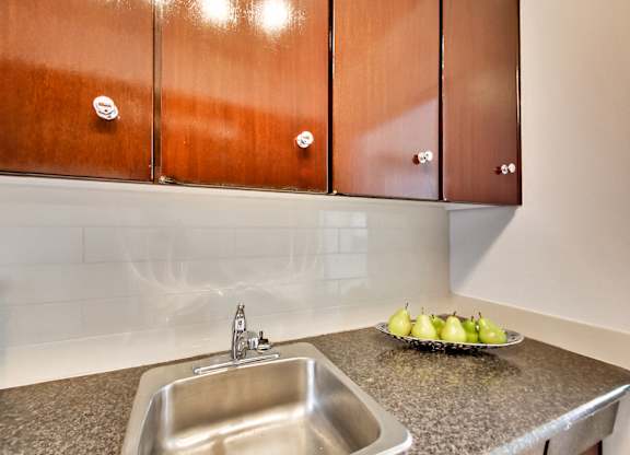 A kitchen with a sink and a bowl of pears on the counter.