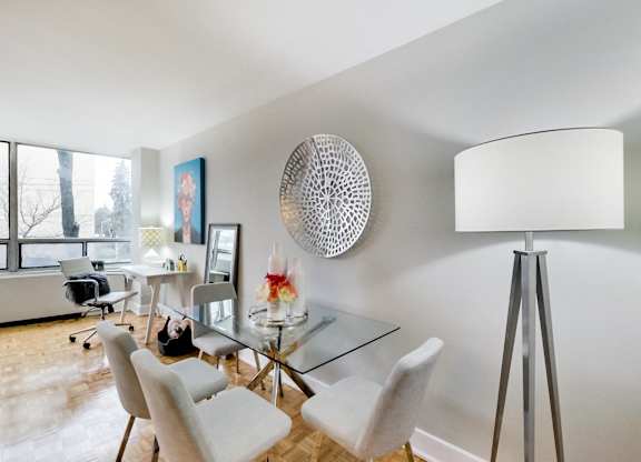 A modern dining room with a glass table and white chairs.
