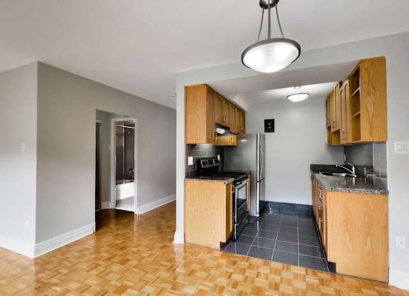 a view of an empty kitchen with wood cabinets and a stainless steel refrigerator