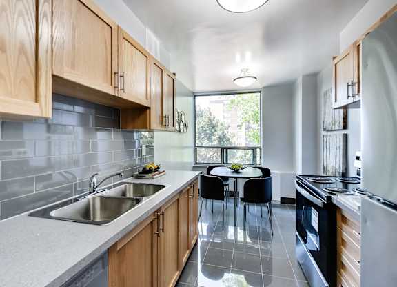 A modern kitchen with wooden cabinets and a large window.