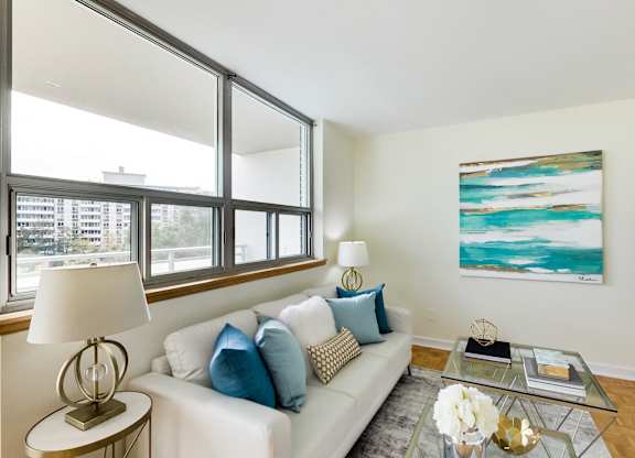 A living room with a white couch, a coffee table, and a painting on the wall.