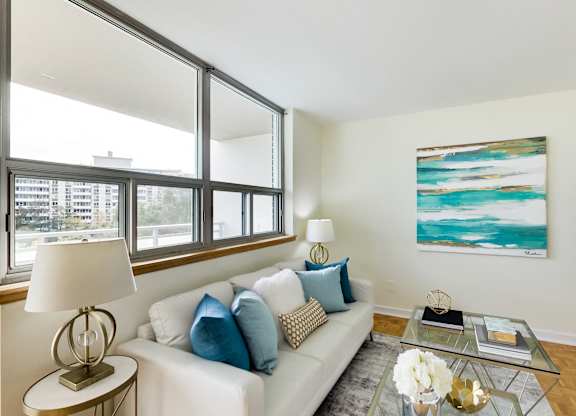 A living room with a white couch, a coffee table, and a painting on the wall.