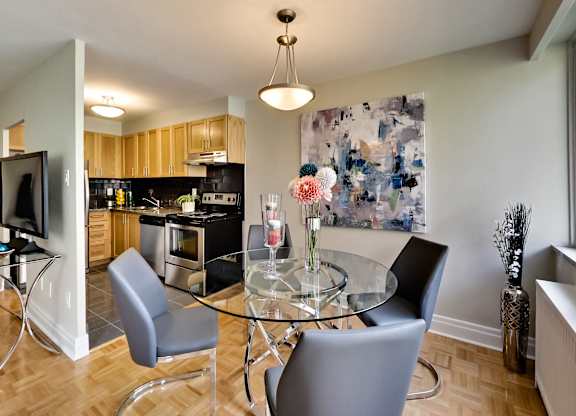 a dining room with a glass table and chairs and a kitchen