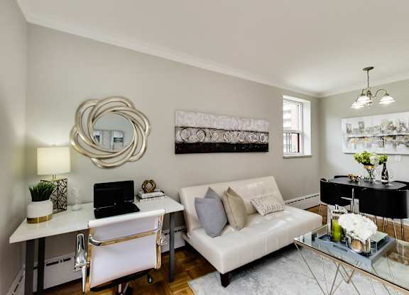 a living room with a white couch and a desk with a laptop