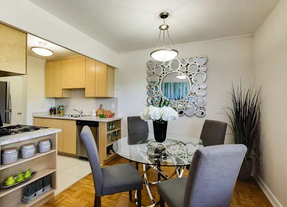 a dining room with a glass table and chairs and a kitchen with a sink and