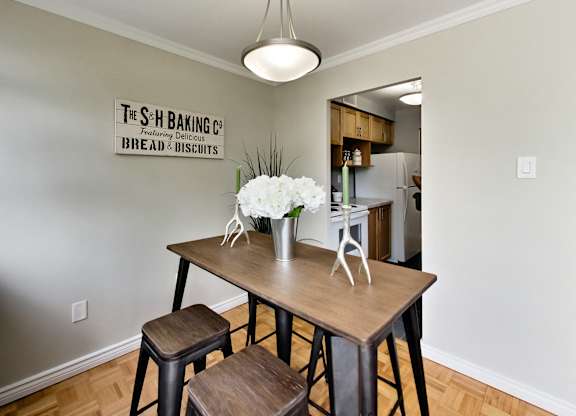 A dining area with a table and chairs and a sign on the wall.