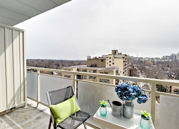 A balcony with a chair and a table with vases on it.