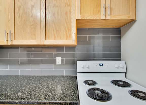 a kitchen with white stove and granite counter top and wooden cabinets