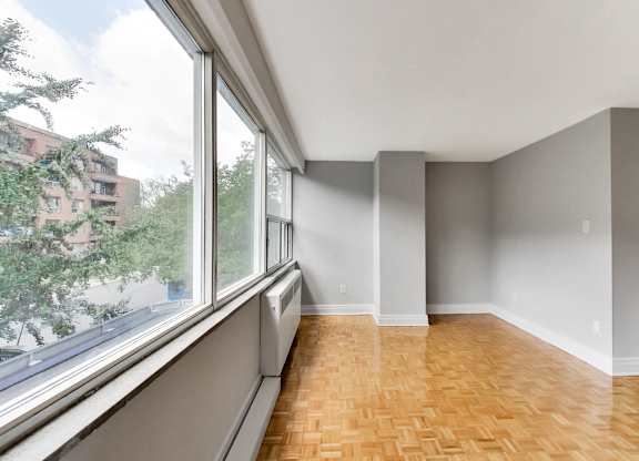 an empty living room with a large window and wood flooring