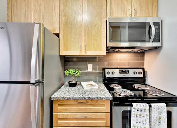 a kitchen with a stove refrigerator and microwave and wooden cabinets